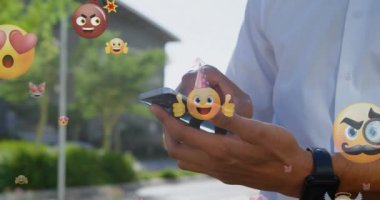 Şehirde akıllı telefon kullanan melez bir adamın elleri yerine duygu simgelerinin animasyonu. küresel bağlantılar, sosyal medya, teknoloji ve dijital arayüz konsepti dijital olarak oluşturulmuş video.