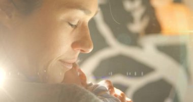 Uyuyan bebekle mutlu beyaz bir annenin üzerinde ışıldayan beneklerin animasyonu. Anneler Günü ve annelik kavramı dijital olarak üretiliyor..