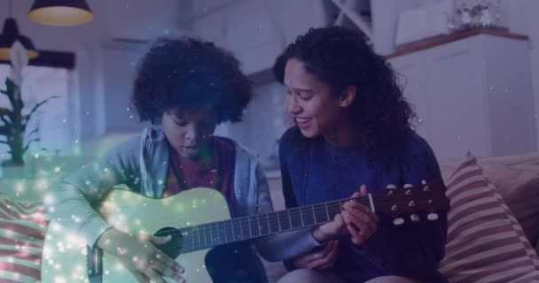 Oğlu Gitar Çalan Mutlu Melez Bir Annenin Üzerindeki Işıldayan Beneklerin — Stok video