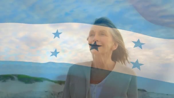 ビーチで幸せなシニア白人女性以上のホンジュラスの旗のアニメーション シニアライフスタイル退職と休日の概念デジタルで生成されたビデオ — ストック動画
