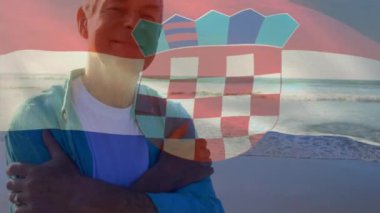 Sahildeki kıdemli beyaz adam yerine Hırvat bayrağının animasyonu. yaşlılar yaşam tarzı, emeklilik ve tatil konsepti dijital olarak oluşturulmuş video.