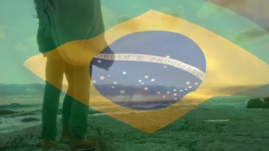 Sahildeki Afrikalı Amerikalı çift üzerinde Brezilya bayrağı animasyonu. Vatanseverlik ve kutlama konsepti dijital olarak oluşturulmuş video.