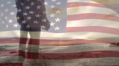 Sahildeki Afro-Amerikan çifti üzerine Amerikan bayrağının animasyonu. Vatanseverlik ve kutlama konsepti dijital olarak oluşturulmuş video.