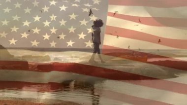 Sahildeki Afro-Amerikan çifti üzerine Amerikan bayrağının animasyonu. Vatanseverlik ve kutlama konsepti dijital olarak oluşturulmuş video.