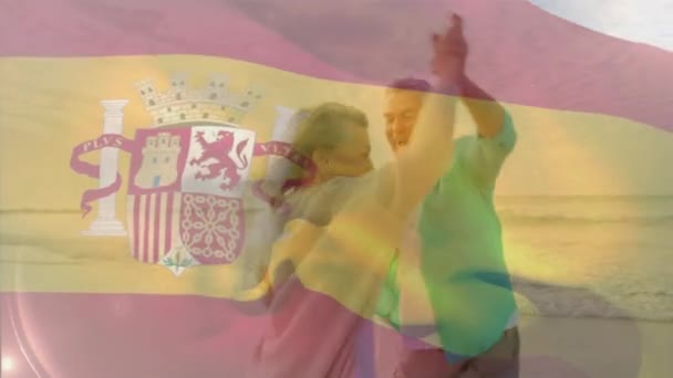 Animacja Flagi Hiszpańskiej Nad Szczęśliwą Starszą Białą Parą Tańczącą Plaży — Wideo stockowe