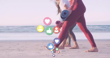 Sahilde yoga minderleri olan çeşitli kadınlar üzerinde medya simgeleri oluşturuluyor. Sosyal medya ve iletişim arayüzü kavramı dijital olarak oluşturulmuş video.