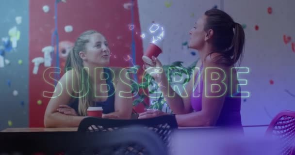 霓虹灯黄色的订阅文字横幅与两个高加索适合的女人在健身房喝咖啡聊天 健身和技术概念 — 图库视频影像