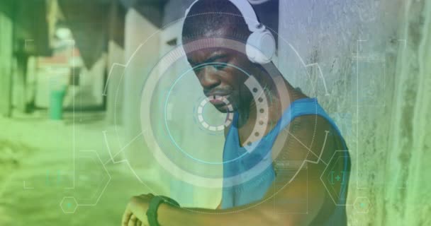 Okrągły Skaner Przeciwko Afrykańskiemu Amerykańskiemu Mężczyźnie Słuchawkach Używającemu Zegarka Zewnątrz — Wideo stockowe