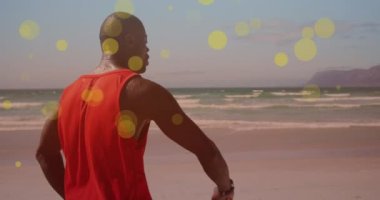 Sahilde akıllı adam kullanan Afro-Amerikan formda bir adama karşı yüzen sarı noktalar. Spor, spor ve teknoloji konsepti