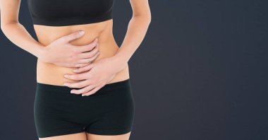 Gri arka planda karın kaslarını fotokopi alanına dayayan formda bir kadının orta kısmı. spor ve spor konsepti