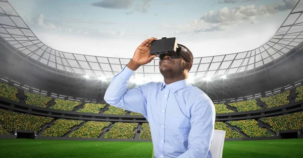 Composite image of african american man wearing vr headset against sports stadium. sports competition and technology concept