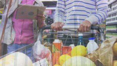 Piyasada tabletle alışveriş yapan farklı çiftlerin orta bölümündeki finansal verilerin animasyonu. ev finansmanı, ekonomi ve teknoloji konseptiyle dijital olarak üretilen video.