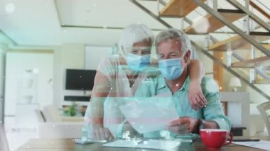 Yüz maskesi takan yaşlı beyaz bir çiftin veri işleme animasyonu. covid 19 pandemik kavramı dijital olarak oluşturulan video sırasında küresel tıp ve dijital arayüz.