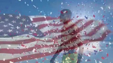 Amerikan bayrağının animasyonu ve Afrika kökenli Amerikalı adamın kumsalda konfeti yemesi. Vatanseverlik ve kutlama konsepti dijital olarak oluşturulmuş video.