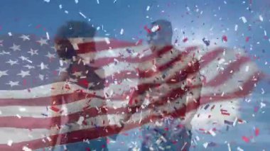 Sahildeki Afro-Amerikan çifti üzerinde Amerikan bayrağı ve konfeti animasyonu. Vatanseverlik ve kutlama konsepti dijital olarak oluşturulmuş video.