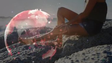 Gün batımında plajda oturan beyaz bir kadının üzerindeki bağlantıların ve dünyanın animasyonu. spor aktif yaşam tarzı, bağlantılar, teknoloji ve dijital arayüz konsepti dijital olarak oluşturulmuş video.