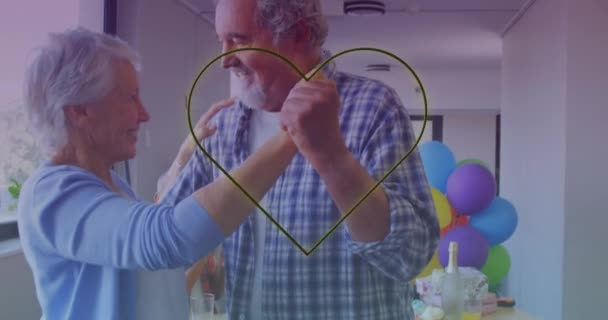 Gelbes Neonfarbenes Herz Gegen Kaukasisches Seniorenpaar Das Bei Einer Geburtstagsparty — Stockvideo