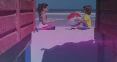 Pink and blue light trails against caucasian brother and sister playing with beach ball at the beach. national siblings day awareness concept