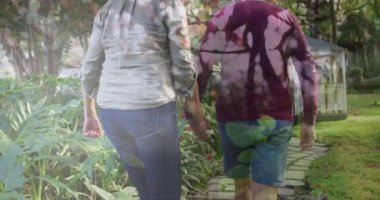 Beyaz tenli yaşlı bir çiftin bahçede yürürken dikiz aynasıyla uzun bir kadının birleşik videosu. Ulusal Yürüyüş Günü Farkındalığı