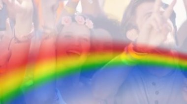 Mutlu insanlardan oluşan bir grubun üzerinde gökkuşağı animasyonu. lgbtq gurur ve eşitlik kutlaması konsepti dijital olarak oluşturulmuş video.