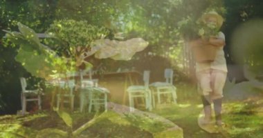 Bahçede bitki saksısı taşıyan Kafkasyalı yaşlı kadına karşı çekilmiş bir video. toplum bahçesi farkındalığı konsepti