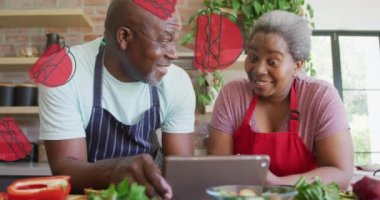 Mutfakta dijital tablet kullanan Afro-Amerikan yaşlı çifte karşı birden fazla hamburger ikonu. yemek konsepti
