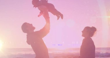 Kumsalda bebekleri olan beyaz mutlu bir çiftin üzerinde ışık lekeleri. Babalar Günü ve kutlama konsepti dijital olarak oluşturulmuş video.