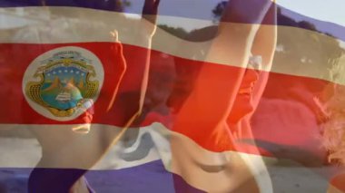 Sahildeki bir grup arkadaşın üzerinde Costa rica bayrağı sallamanın animasyonu. seyahat ve tatil konsepti, dijital olarak üretilen video.