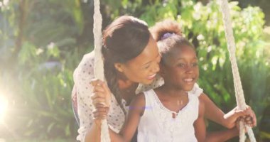 Afrikalı Amerikalı 'ya karşı bir ışık noktası kızını salıncakta sallıyor. toplum bahçesi farkındalığı konsepti