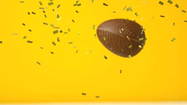 Animation Gold Confetti Chocolate Easter Egg Falling Bouncing Yellow Background — Stock Video