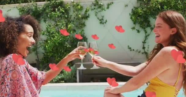 许多红心飘浮在两个不同的女性朋友面前 在游泳池边敬酒 旅行和休假概念 — 图库视频影像