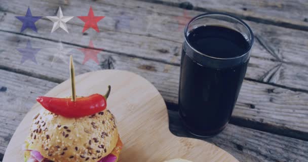 ハンバーガーの上に星のアニメーションや木製のテーブルの上で飲む アメリカ料理とファーストフードのコンセプトをデジタルで生成したビデオ — ストック動画