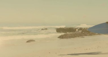 Sahilde sörf tahtası olan Afro-Amerikan bir çiftin üzerindeki ışığın animasyonu. su sporları, aktif yaşam tarzı ve tatiller dijital olarak üretilen video konsepti.