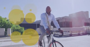 Şehirde bisiklete binen Afrikalı Amerikalı iş adamının üzerindeki sarı noktaların animasyonu. Sağlıklı aktif yaşam tarzı, şehir konseptinde dijital olarak üretilen video.