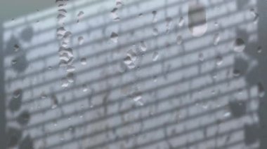Gri arka planda pencere gölgesinde yağmur damlalarının canlandırılması. gölge, desen ve renk konsepti dijital olarak oluşturulmuş video.