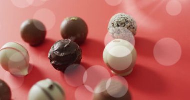 Kırmızı yüzeyde çikolatalı pralinaların üzerindeki ışığın animasyonu. tatlılar, tatlılar ve dijital olarak üretilen çikolata konsepti.