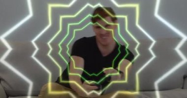 Animation of tunnel with neon shapes over caucasian man playing video games. global technology, social media and digital interface concept digitally generated video.