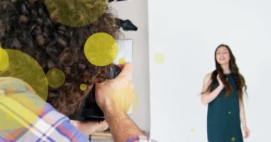 Kafkasyalı erkek fotoğrafçı ve kadın modelin fotoğraf çektiği sarı noktaların animasyonu. Fotoğraf, optik ve fotoğrafçılık mesleği kavramı dijital olarak oluşturuldu.