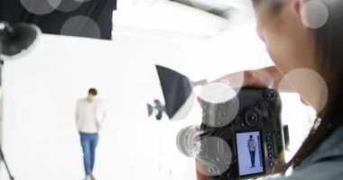 Animation of white dots over caucasian female photographer and male model taking photos. photography, optics and photographer profession concept digitally generated video.