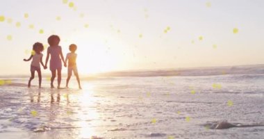 Güneşli sahilde çocuklu mutlu Afrikalı Amerikalı annelerin üzerindeki beneklerin animasyonu. Dijital ortamda üretilen sağlıklı ve aktif plaj tatili konsepti.