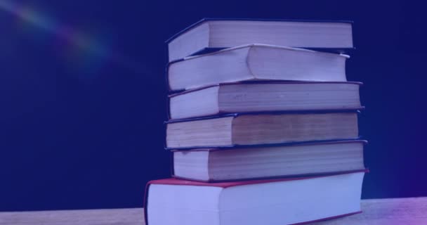 青い背景の本の山の上に輝く光のアニメーション 国際的な読み書きの日とデジタルで生成されたビデオ — ストック動画