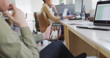 Caucasian businessman using smartphone for video call with biracial business colleague. business communication technology, digital composite video.