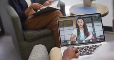 Çift ırklı iş arkadaşlarıyla görüntülü konuşma için bilgisayarını kullanan Afro-Amerikalı iş adamı. ticari iletişim teknolojisi, dijital kompozit video.