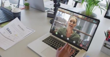 Kafkasyalı iş arkadaşı ile video görüşmesi için bilgisayarını kullanan Afrikalı Amerikalı iş kadını. ticari iletişim teknolojisi, dijital kompozit video.