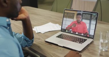 Afrikalı Amerikalı iş arkadaşlarıyla video görüşmesi için bilgisayarını kullanan Afro-Amerikalı iş adamı. ticari iletişim teknolojisi, dijital kompozit video.