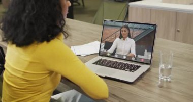 Çift ırklı iş kadını çift ırklı iş arkadaşlarıyla görüntülü konuşma için dizüstü bilgisayar kullanıyor. ticari iletişim teknolojisi, dijital kompozit video.