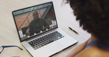 Afrikalı Amerikalı iş arkadaşı ile video görüşmesi için bilgisayarını kullanan Afro-Amerikalı bir iş kadını. ticari iletişim teknolojisi, dijital kompozit video.
