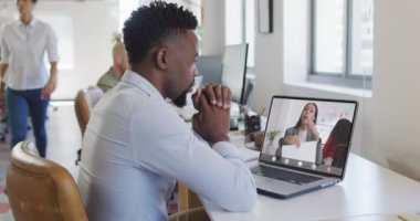 Çift ırklı iş arkadaşlarıyla görüntülü konuşma için bilgisayarını kullanan Afro-Amerikalı iş adamı. ticari iletişim teknolojisi, dijital kompozit video.