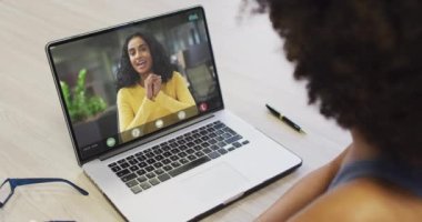Çift ırklı iş arkadaşlarıyla video görüşmesi için bilgisayarını kullanan Afrikalı Amerikalı bir iş kadını. ticari iletişim teknolojisi, dijital kompozit video.