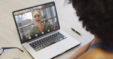 Kafkasyalı iş arkadaşı ile video görüşmesi için bilgisayarını kullanan Afrikalı Amerikalı iş kadını. ticari iletişim teknolojisi, dijital kompozit video.